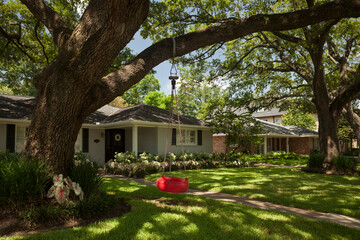 Red tire swing hanging from a tree at the detached residential house garden in Afton Oaks, Houston  - Powered by Adobe