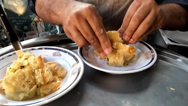 Chef hand close view Breaking or crushing samosa in plate for samosa chat, pakistani and indian street food