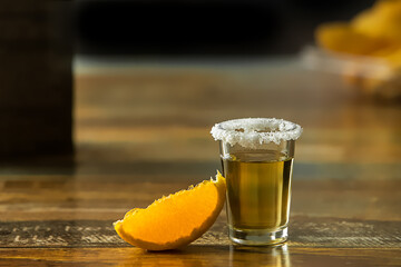 tequila shot drink in a glass decorated with salt with slice of fresh lemon, splash of the drink,...