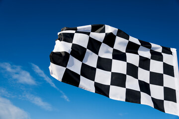 Checkered race flag waving on sky