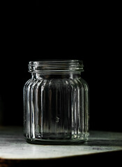 empty glass jar or shot drink jar over dark black background, transparent glass