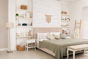 Stylish room interior with large comfortable bed, wall shelves and beautiful decor elements