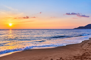 Fototapeta na wymiar Landscape of scenic idyllic peaceful calm sky wallpaper with sea waves coast and sandy beach at golden sunset