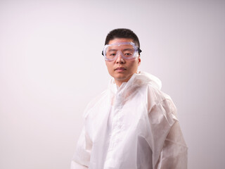 A health care worker wearing a mask and protective clothing on a solid color background