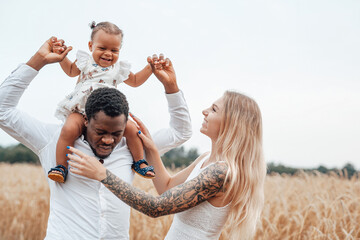 Father riding his child on his shoulders in wheat fields