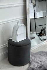 Stylish white backpack on pouf in dressing room