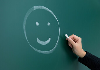 Hand drawing smiley face on blackboard
