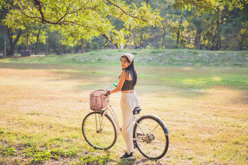 Obraz premium Portrait Asian woman in a green singlet sitting on a bicycle on a lawn with nature background in a park