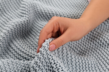 Woman touching soft grey knitted fabric, closeup