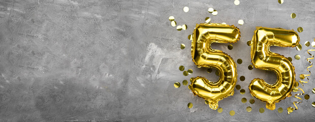 Yellow foil balloon number, number fifty five concrete background. Greeting card with the...