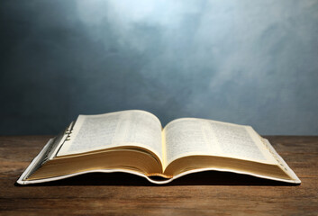 Open Bible on wooden table against color background. Christian religious book