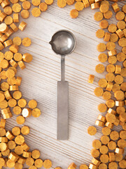 Sealing wax metal spoon and yellow gold sealing wax granules or beads a lot on wooden background....