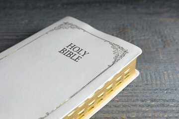 Old hardcover Bible on grey wooden table, closeup. Religious book
