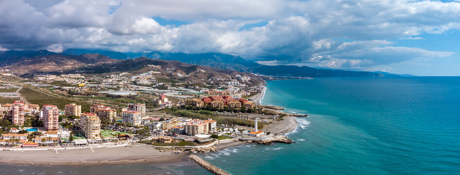 Drone perspective of costal city of Torrox situated in Malaga, Costa del Sol, Spain. Touristic travel destination. View of the promenade and beach area. The lighthouse of Torrox and the river.