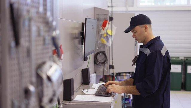 Mechanic in uniform use computer for his job for fixing broken car