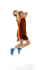 Portrait of young sportive girl in motion, playing basketball, training isolated over white studio background