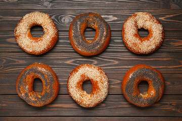 Many delicious fresh bagels on wooden table, flat lay
