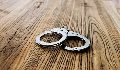 Steel handcuffs on wooden table