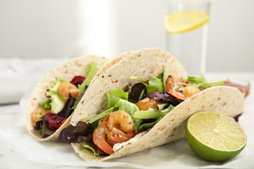 Delicious tacos with shrimps and lime on white table, closeup