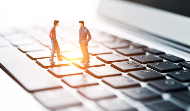 Miniature workers standing on top of keyboard - Powered by Adobe