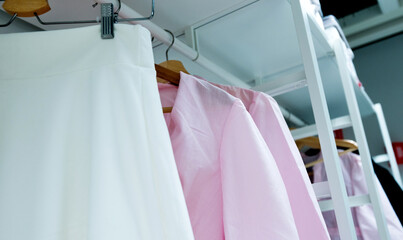 Row of cloth hangers with female pink shirts