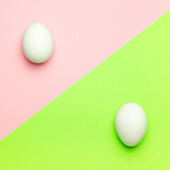 White eggs on a green and pink background. Easter concept.
