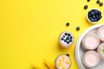 Tasty yogurt in glass jars and ingredients on yellow background, flat lay. Space for text