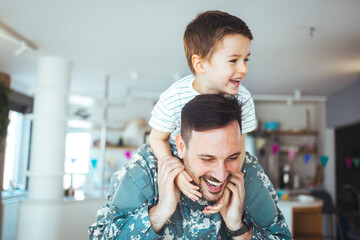 Young soldier just arrived home and he is so happy to see his son. Young man in military uniform with his little son at home. My Hero is back home
