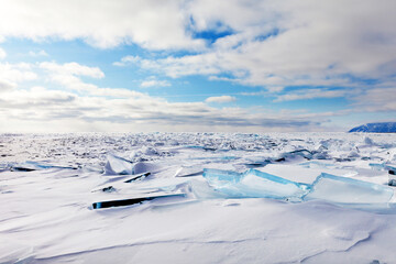An unusual winter landscape of a frozen Baikal Lake with snowy ice hummock fields with transparent...