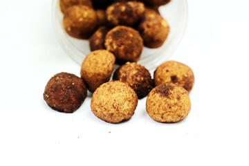 Tasty sweet chocolate truffles on a white table with a container on the background