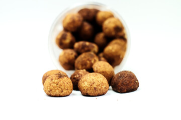 Tasty sweet chocolate truffles on a white table with a container on the background