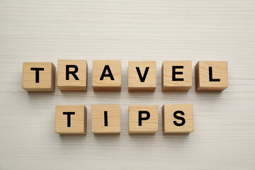 Phrase Travel Tips made with cubes on white wooden table, flat lay