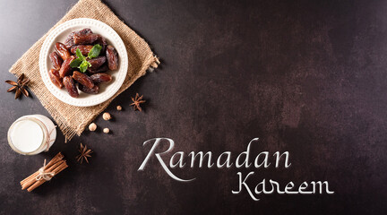 Top view image of decoration Ramadan Kareem, dates fruit and milk with the text on dark stone background.