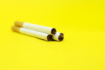 Cigarettes on a yellow surface background with a copy space