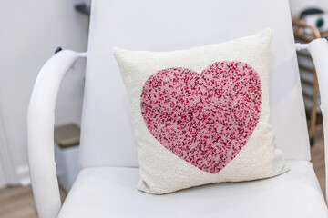 Valentine's day heart shaped pillow sitting on a white medical patient chair in a medical clinic