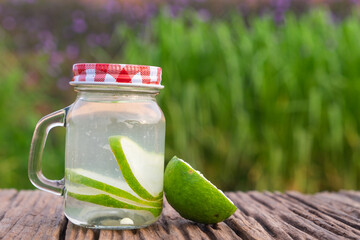 Detox water with lime in jar against rustic wood.