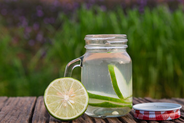 Detox water with lime in jar against rustic wood.
