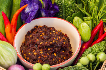 Thai chili paste,Chili paste in a white ceramic cup surrounded by green vegetables and fresh red chilies.