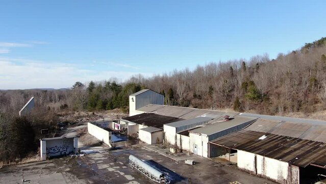 Aerial Drone Footage Orbiting Left Around an Abandoned, Decaying Warehouse on the edge of a Forest.