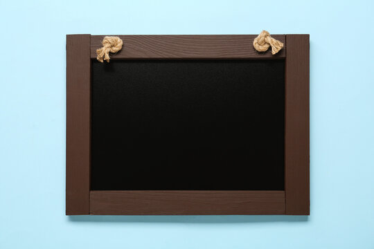 Clean small black chalkboard on light blue background, top view