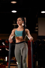 Beautiful young woman with barbell weight plate working out in sports club