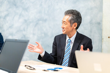 スーツで意見を述べる経営者