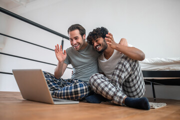Cheerful biracial couple greeting someone via Skype