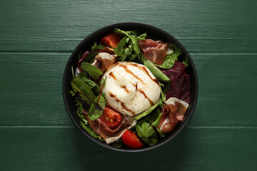 Delicious burrata salad on green wooden table, top view