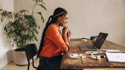 Smiling graphic designer attending an online meeting in her office - obrazy, fototapety, plakaty