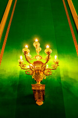 gilded lamp on a green wall in the palace interior