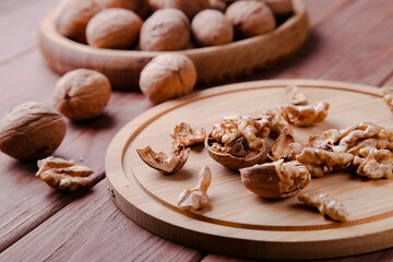 Walnuts in a shell in a wooden plate on a brown background. Healthy food concept