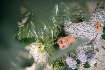 Portrait of a young woman lying relaxed on the floor among the flowers. View from above.