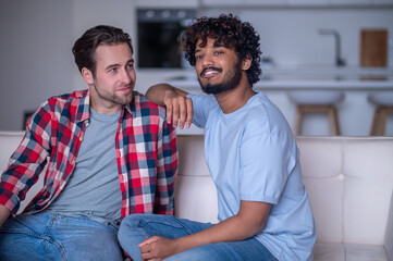 Fototapeta premium Romantic biracial gay couple sitting on the sofa