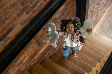 Top view of girl showing toys to camera